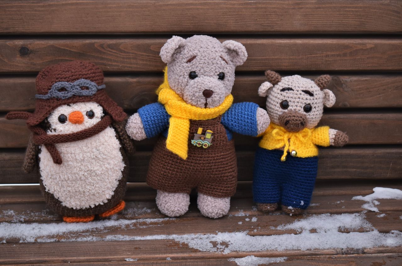 our-story Amigurumi crochet toys placed on a snowy wooden bench. Perfect for winter and craft themes.