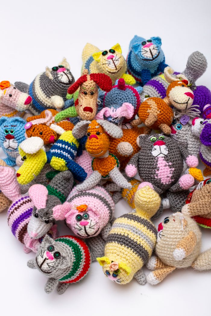 who-we-are Vibrant assortment of handmade knitted animal toys on a white background.